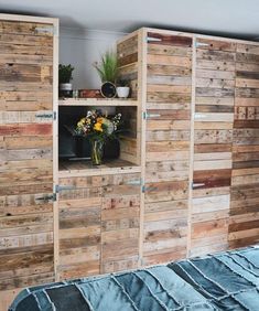 a bedroom with wooden walls and shelves made out of pallet wood, flowers in a vase on the bed