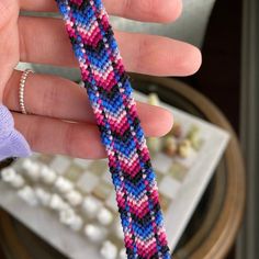 a hand is holding a colorful bracelet on it's fingers and the beads are beaded