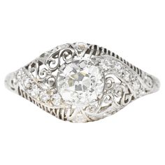 Bombè band ring is pierced with linear striation alternating with scrolled filigree. Centering an old mine cut diamond weighing 0.95 carat - J color with VS2 clarity. With single cut diamond accents weighing collectively approximately 0.30 - eye clean and bright. Completed by engraved floral with foliate shoulders. Stamped for platinum. Circa: 1910. Ring Size: 6 3/4 & sizable. Measures: North to South 10.5 mm and sits 7.2 mm high. Total weight: 4.3 grams. GIA Diamond Dossier: 2191586688. Fancifully. Decorative. Torsion. Stock Number: We-9226 Scroll Engagement Ring, Filigree Engagement Ring, Old Mine Cut Diamond, European Cut Diamonds, Gia Diamond, Jewelry Rings Engagement, Estate Jewelry, Anniversary Rings, Band Ring