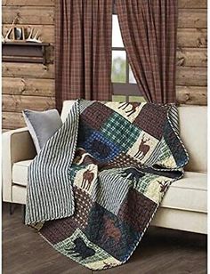 a living room with a couch, chair and window covered in a plaid bear quilt