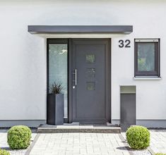 the front door of a house with two planters on either side and number 32