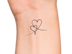 a small tattoo on the wrist of a woman's arm with two hearts in it