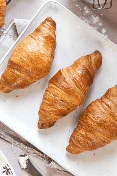 three croissants sitting on top of a white tray