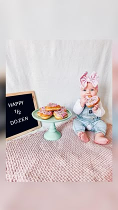 a baby doll sitting next to a sign with doughnuts on it