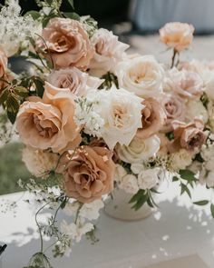 a vase filled with lots of flowers sitting on top of a white table covered in greenery