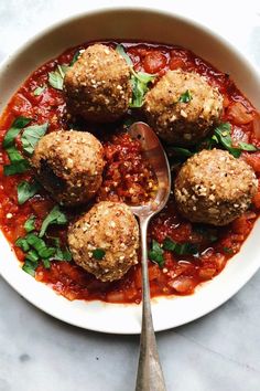 a white bowl filled with meatballs covered in marinara sauce