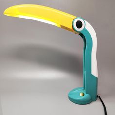 a blue and yellow lamp with a bird's eye on it, sitting in front of a gray background