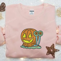 a pink t - shirt with an image of a pumpkin on the front and two small stars around it