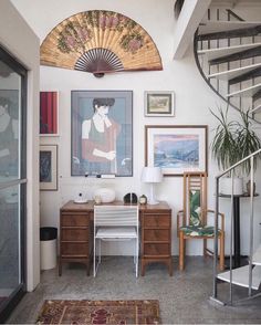 a living room filled with furniture and art on the wall next to a spiral staircase