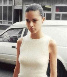 a woman walking down the street in front of a car