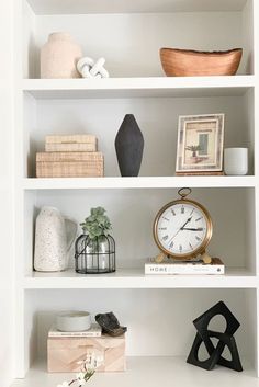 a white book shelf filled with books and vases