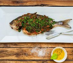 a white plate topped with a fish covered in herbs