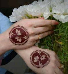 two hands with henna tattoos on their palms and white flowers in front of them