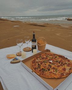 a pizza sitting on top of a table next to a bottle of wine and two glasses