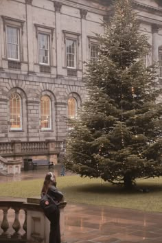 a woman sitting on a bench in front of a christmas tree