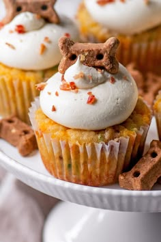 several cupcakes with white frosting and toppings on a plate