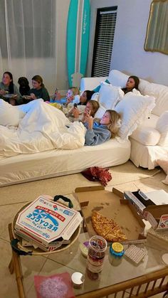 a group of people laying on top of a bed in a living room next to each other