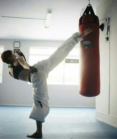 a man doing a handstand in front of a punching bag