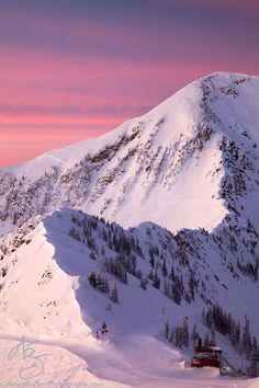 a mountain covered in snow under a pink sky