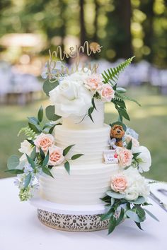 a white wedding cake with flowers and greenery