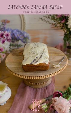 a cake with white frosting sitting on top of a wooden table next to flowers