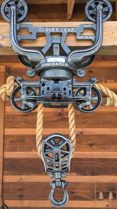 a close up of a metal object on a wooden wall with ropes hanging from it