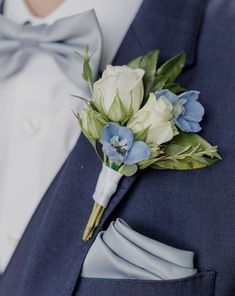 a man wearing a blue suit and bow tie is holding a boutonniere