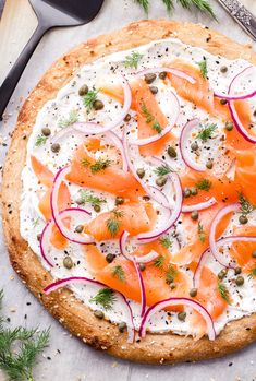 a pizza topped with smoked salmon, capers and onions