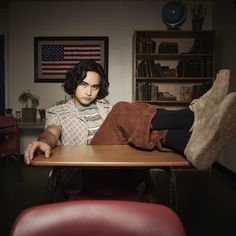 a man sitting at a table with his feet on top of the table and legs crossed