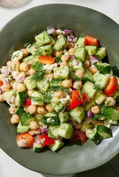 a salad with cucumbers, tomatoes, and other vegetables in a green bowl