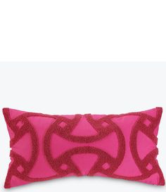 a pink and red pillow with an intricate design on the front, sitting on a white surface