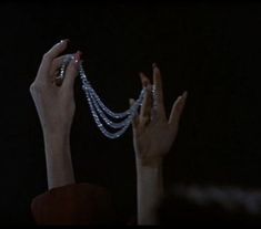 two hands reaching up to the sky with pearls on their fingers and bracelets hanging from them