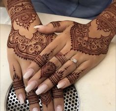 two hands with henna tattoos on them and one holding the other's hand