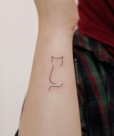 a small cat tattoo on the left wrist is shown in front of a woman's arm