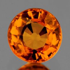 an orange diamond is shown on a reflective surface with its reflection in the glass top