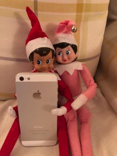 two elfs are sitting next to an iphone