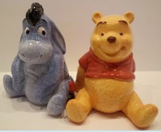 two winnie the pooh figurines sitting next to each other