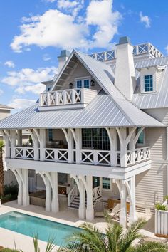 a large white house with a pool in the front yard and covered porchs on both sides