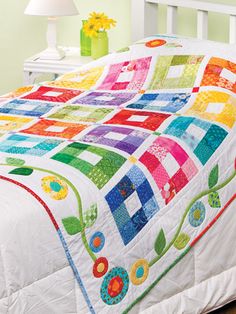 a white bed topped with a colorful quilt