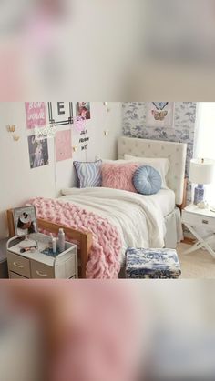 a white bed topped with pillows and blankets next to a wall covered in pictures on the walls