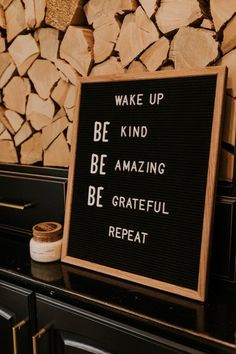 a sign that says wake up be kind of amazing be grateful repeat on it next to firewood