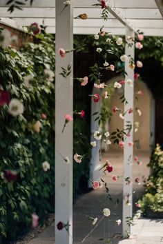 flowers hanging from the side of a white pergoline