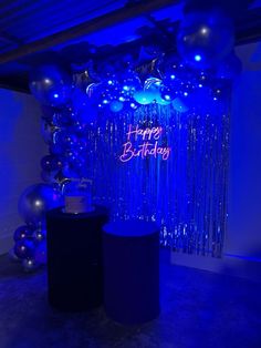 a birthday party with balloons and streamers on the wall, blue lights in the background