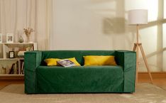 a living room with a green couch and yellow pillows on the pillowcase, next to a book shelf filled with books