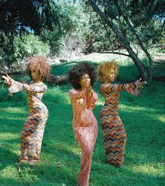 three women standing in the grass with their arms outstretched