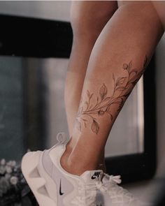 a woman's legs with tattoos on them and white nike sneakers in front of a mirror