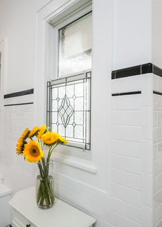 a white bathroom with sunflowers in a vase