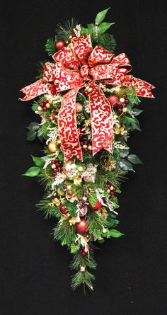 a christmas wreath with red and white bows on it's sides, surrounded by greenery