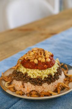 a white plate topped with rice covered in beans and sauce on top of a blue table cloth