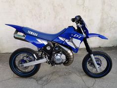 a blue and white motorcycle parked next to a wall